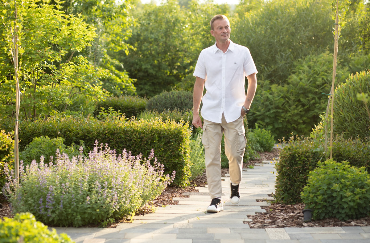 садовник в соломенной шляпе. почему стоит садовое сейчас. дачный домик на участке. красивый огород. хвойники вдоль террасы.